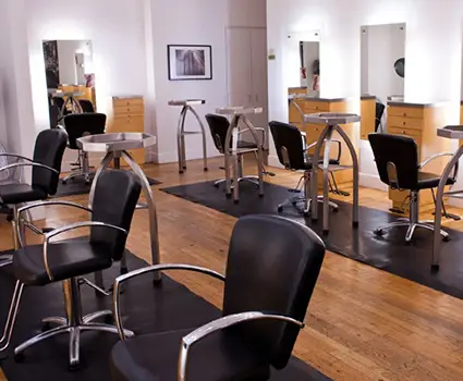 - Paris Parker Aveda Salons and Spas - Baton Rouge, New Orleans, Mandeville, LA A modern hair salon and day spa interior with several black styling chairs, round mirrors, and wooden floors. The space is clean, well-lit, and organized—perfect for your next balayage or beauty treatment. - Paris Parker Aveda Salons and Spas - Baton Rouge, New Orleans, Mandeville, LA