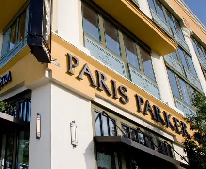 - Paris Parker Aveda Salons and Spas - Baton Rouge, New Orleans, Mandeville, LA Exterior of a building with large windows and a sign reading "Paris Parker" above the entrance, highlighting this Aveda Salon and Day Spa. - Paris Parker Aveda Salons and Spas - Baton Rouge, New Orleans, Mandeville, LA