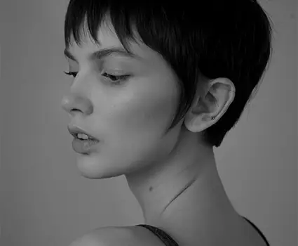 - Paris Parker Aveda Salons and Spas - Baton Rouge, New Orleans, Mandeville, LA Black and white photo of a person with a fresh haircut, looking slightly over their shoulder with a neutral expression. - Paris Parker Aveda Salons and Spas - Baton Rouge, New Orleans, Mandeville, LA
