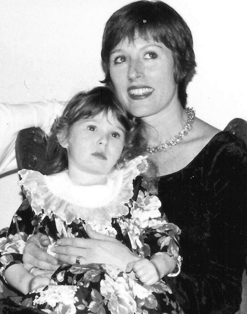 - Paris Parker Aveda Salons and Spas - Baton Rouge, New Orleans, Mandeville, LA A woman in a dark dress with a pearl necklace, her haircut perfectly styled, holds a young girl in a floral dress with a ruffled collar. Both are looking slightly away from the camera. - Paris Parker Aveda Salons and Spas - Baton Rouge, New Orleans, Mandeville, LA