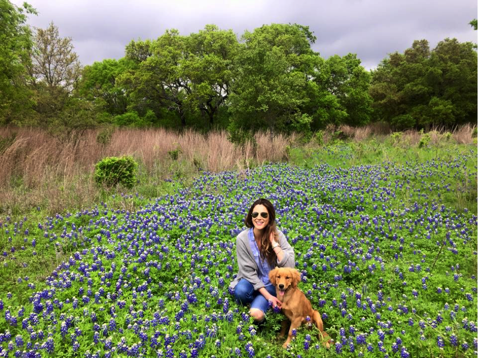 - Paris Parker Aveda Salons and Spas - Baton Rouge, New Orleans, Mandeville, LA Woman with a fresh balayage sitting in a field of bluebonnet flowers, holding a golden retriever puppy on a leash; trees and a cloudy sky in the background. - Paris Parker Aveda Salons and Spas - Baton Rouge, New Orleans, Mandeville, LA