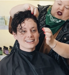 - Paris Parker Aveda Salons and Spas - Baton Rouge, New Orleans, Mandeville, LA A person with short, wet hair sits smiling while another styles their hair in a hair salon, getting ready for a fresh haircut. - Paris Parker Aveda Salons and Spas - Baton Rouge, New Orleans, Mandeville, LA