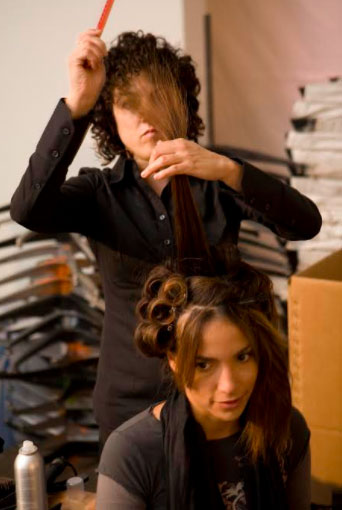 - Paris Parker Aveda Salons and Spas - Baton Rouge, New Orleans, Mandeville, LA A hairstylist at an Aveda Salon uses a comb to lift a section of a seated woman's hair while styling it, with hair rollers and products visible nearby. - Paris Parker Aveda Salons and Spas - Baton Rouge, New Orleans, Mandeville, LA