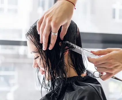 - Paris Parker Aveda Salons and Spas - Baton Rouge, New Orleans, Mandeville, LA A person with wet hair sits in a Hair Salon chair while a stylist gives them a precise haircut with scissors. - Paris Parker Aveda Salons and Spas - Baton Rouge, New Orleans, Mandeville, LA