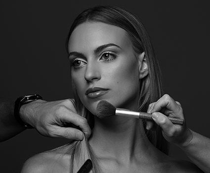 - Paris Parker Aveda Salons and Spas - Baton Rouge, New Orleans, Mandeville, LA A woman with straight hair receives a facial at a day spa as makeup is applied to her cheek, while another hand holds a section of her hair; the image is in black and white. - Paris Parker Aveda Salons and Spas - Baton Rouge, New Orleans, Mandeville, LA
